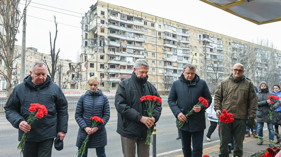 El Alto Comisionado Filippo Grandi (al centro), junto a representantes de las autoridades locales, coloca flores en un edificio residencial destruido durante un ataque con misiles el 14 de enero de 2023, en la ciudad de Dnipro, Ucrania.