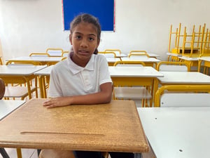 Una niña sentada en un pupitre en un salón de clases