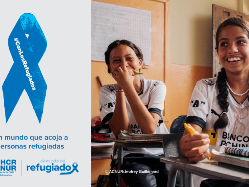 A la derecha, una foto de dos chicas jóvenes sonriendo y sentadas en sus pupitres en un aula. A la izquierda, un listón azul con la inscripción “Con los refugiados”. Debajo de la cinta se lee: “Por un mundo que acoja a las personas refugiadas”.