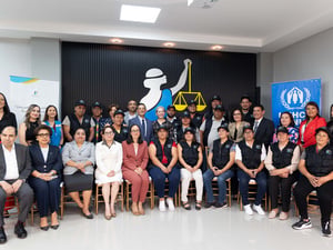 21 personas están de pie, detrás de 11 personas que están sentadas en sillas doradas