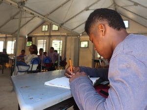 Niño sigue clases en una estructura prefabricada.