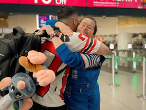 Un hombre se despide de una mujer con un abrazo en un aeropuerto.