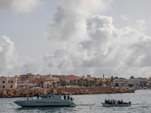Un barco que transportaba a 13 refugiados y migrantes de Túnez y Marruecos es remolcado por un buque patrullero italiano al puerto de Lampedusa en octubre de 2020.
