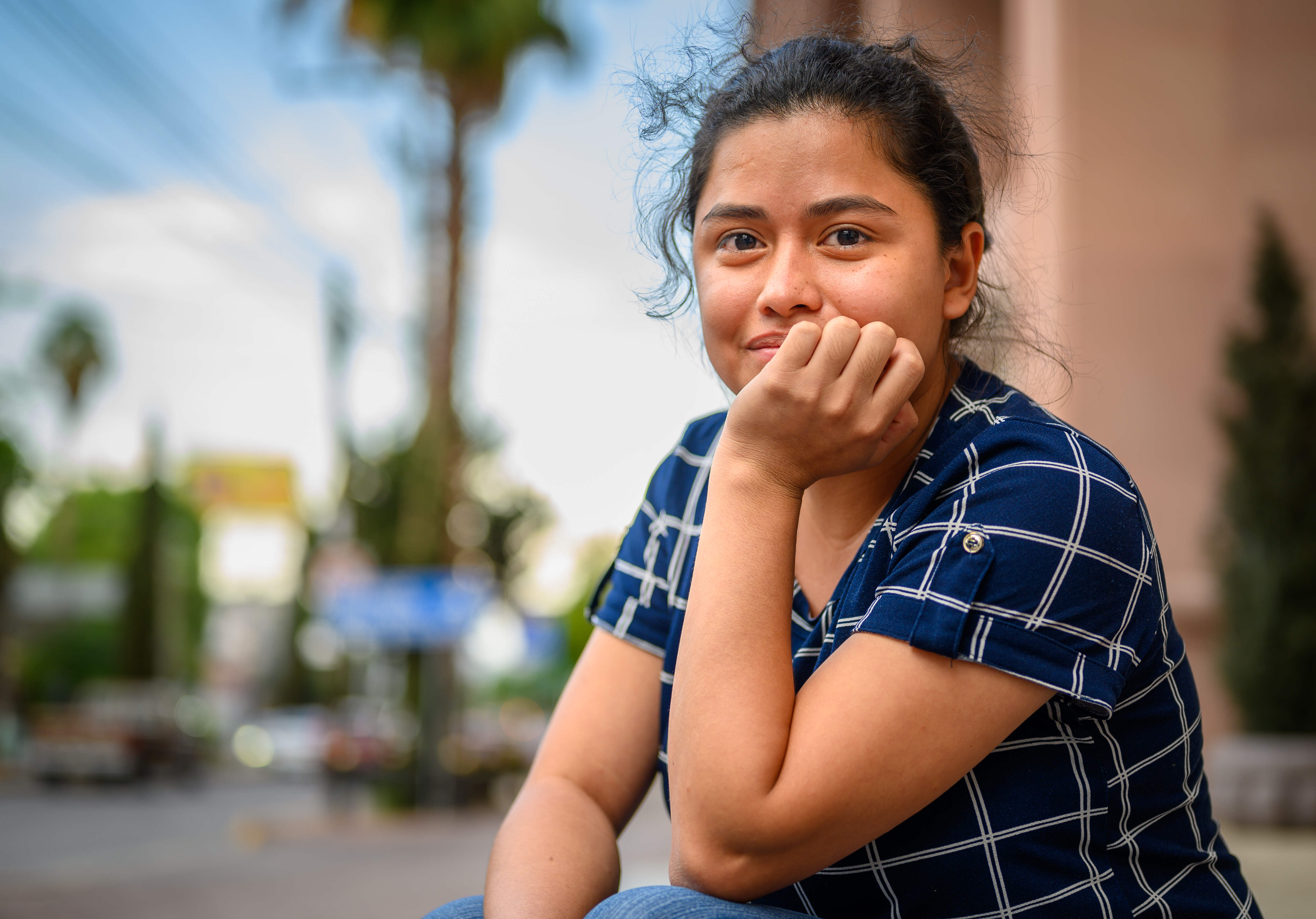 Una joven con camisa manga corta azul de cuadros, posa para la cámara.