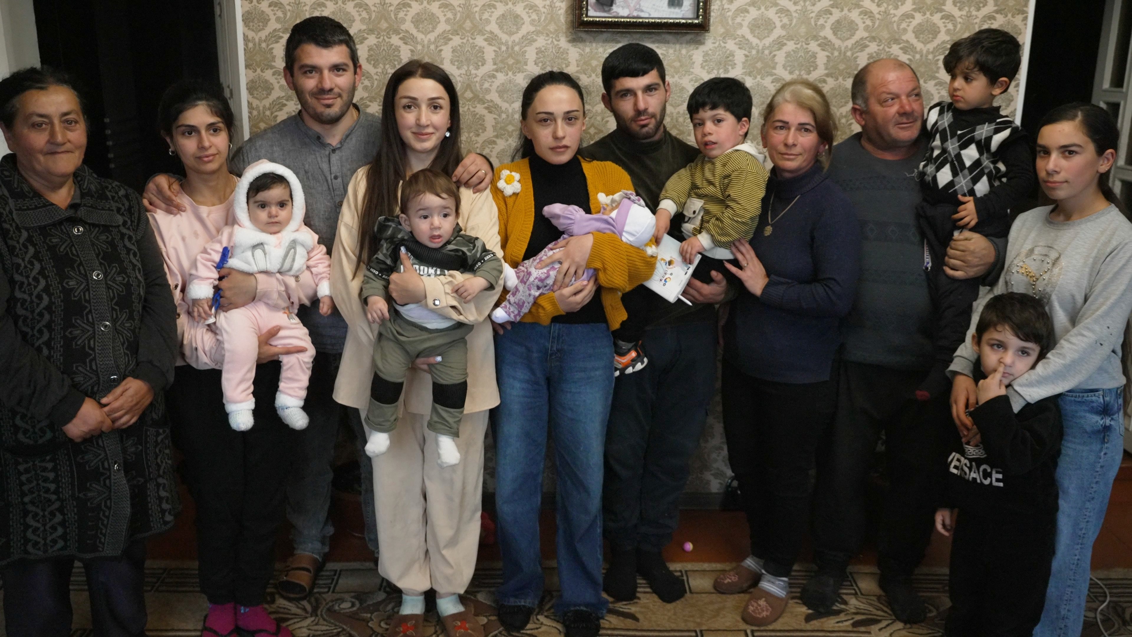Una familia posa para una foto de grupo en la sala de su casa.