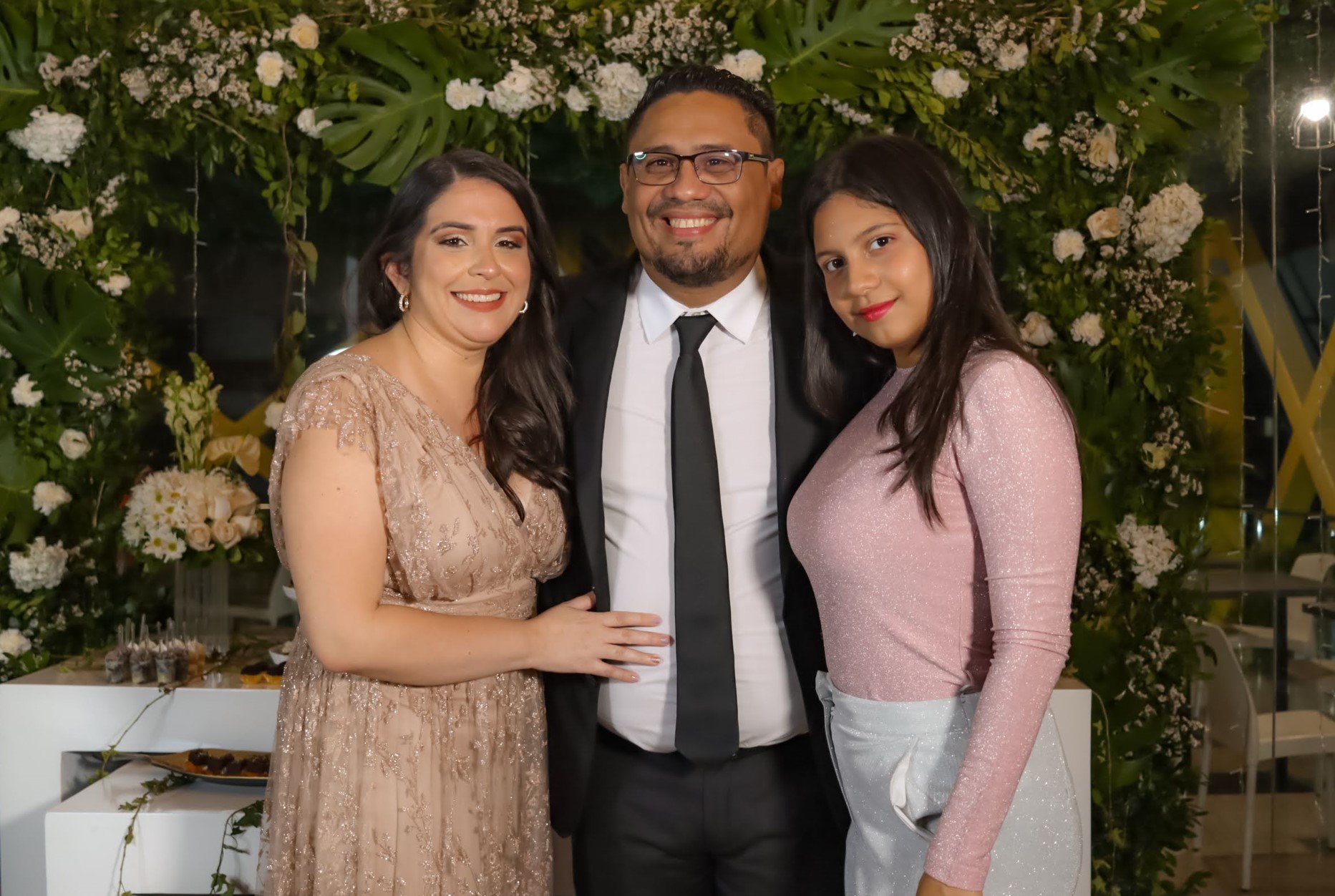 Una familia compuesta por un hombre, una mujer y una niña posa para una foto sonriendo.
