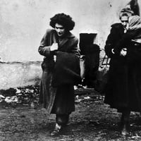 Fotografía en blanco y negro de tres mujeres con un niño que llegan a un campamento de refugiados en Austria
