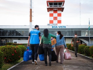 Un grupo de refugiados y migrantes de Venezuela en el aeropuerto de Boa Vista, acompañados por un trabajador de ACNUR.