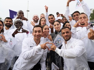 Un grupo de jóvenes vestidos con prendas deportivas blancas forman con los dedos emojis de corazones.