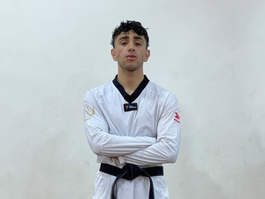 Un joven viste uniforme blanco de Taewkondo con cinturón negro