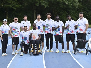 Atletas con uniformes a juego posan para una foto grupal en una pista de atletismo.
