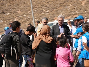 Filippo Grandi y otras personas con chalecos de ACNUR charlan con una familia.