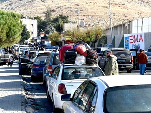 Una calle llena de vehículos cargados de pertenencias.