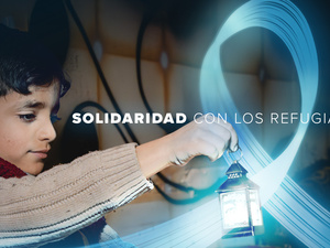 Un niño sostiene una linterna en un recinto oscuro. Una luz azul en forma de lazo rodea la linterna. En medio de la imagen se lee "Solidaridad con los refugiados".
