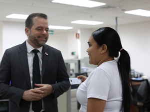 Un hombre y una mujer conversan en una oficina. La mujer tiene en su mano derecha un carné.