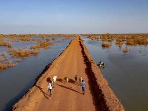 Vaerias personas sobre un largo camino de tierra rodeado de agua por ambos lados