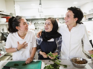 Tres mujeres sonríen mientras cocinan