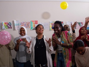 Mujeres aplauden, sonríen y lanzan globos al aire