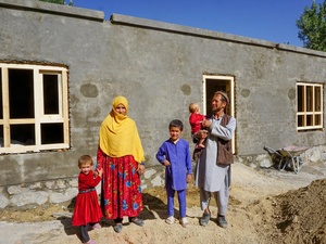 Un hombre con su hijo en brazos junto a su esposa y sus dos hijos delante de un apartamento recién construido