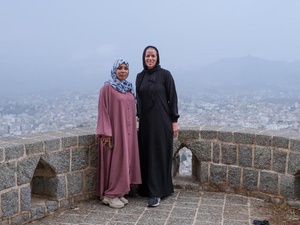 Dos mujeres posan juntas para una foto en un punto panorámico de una ciudad.