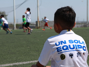 Niño observa el juego de sus compañeros mientras espera su turno para participar en las ligas sociales de fútbol que forman parte de las actividades de coexistencia pacífica de ACNUR en Nuevo León.