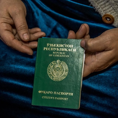 Enfoque de las manos de una mujer que sostiene un pasaporte inválido de Uzbekistán