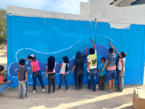 Niñas y niños pintan un mural como parte de las actividades de fortalecimiento comunitario en Sinaloa.