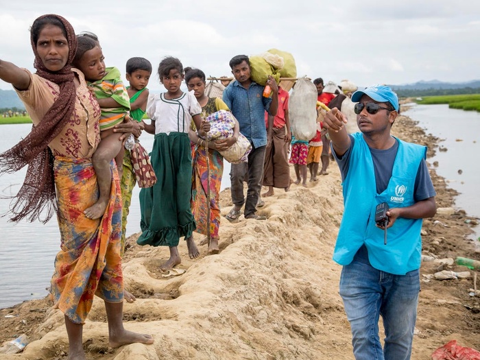 Una trabajadora de ACNUR le indica a un grupo de personas rohingyas refugiadas dónde se encuentra el centro de tránsito. 