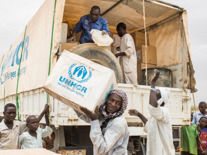 Un grupo de hombres descarga suministros de ACNUR de un camión en Chad
