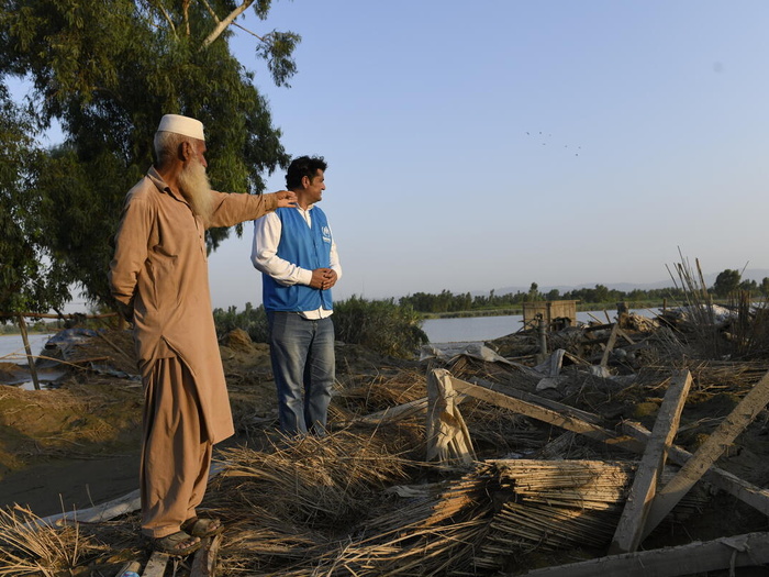 Un refugiado afgano y un trabajador de ACNUR charlan en un espacio afectado por las inundaciones en Pakistán