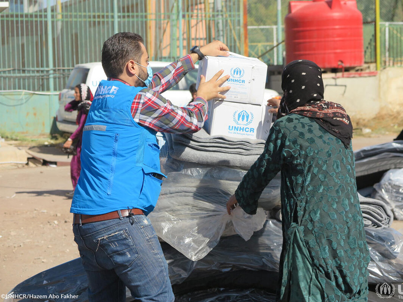 Two people unpack UNHCR boxes and blankets in Syria 
