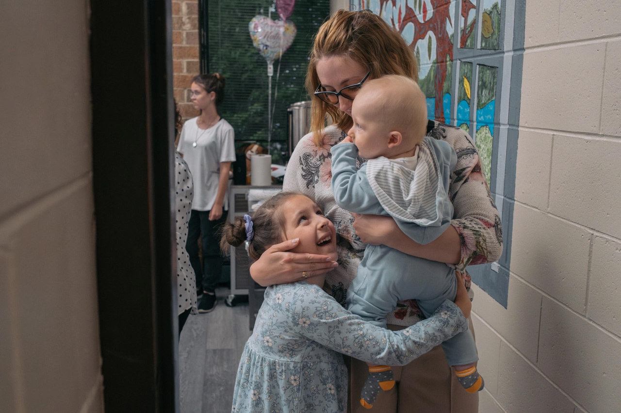 Una mujer abraza a sus hijos: un bebé y una niña pequeña