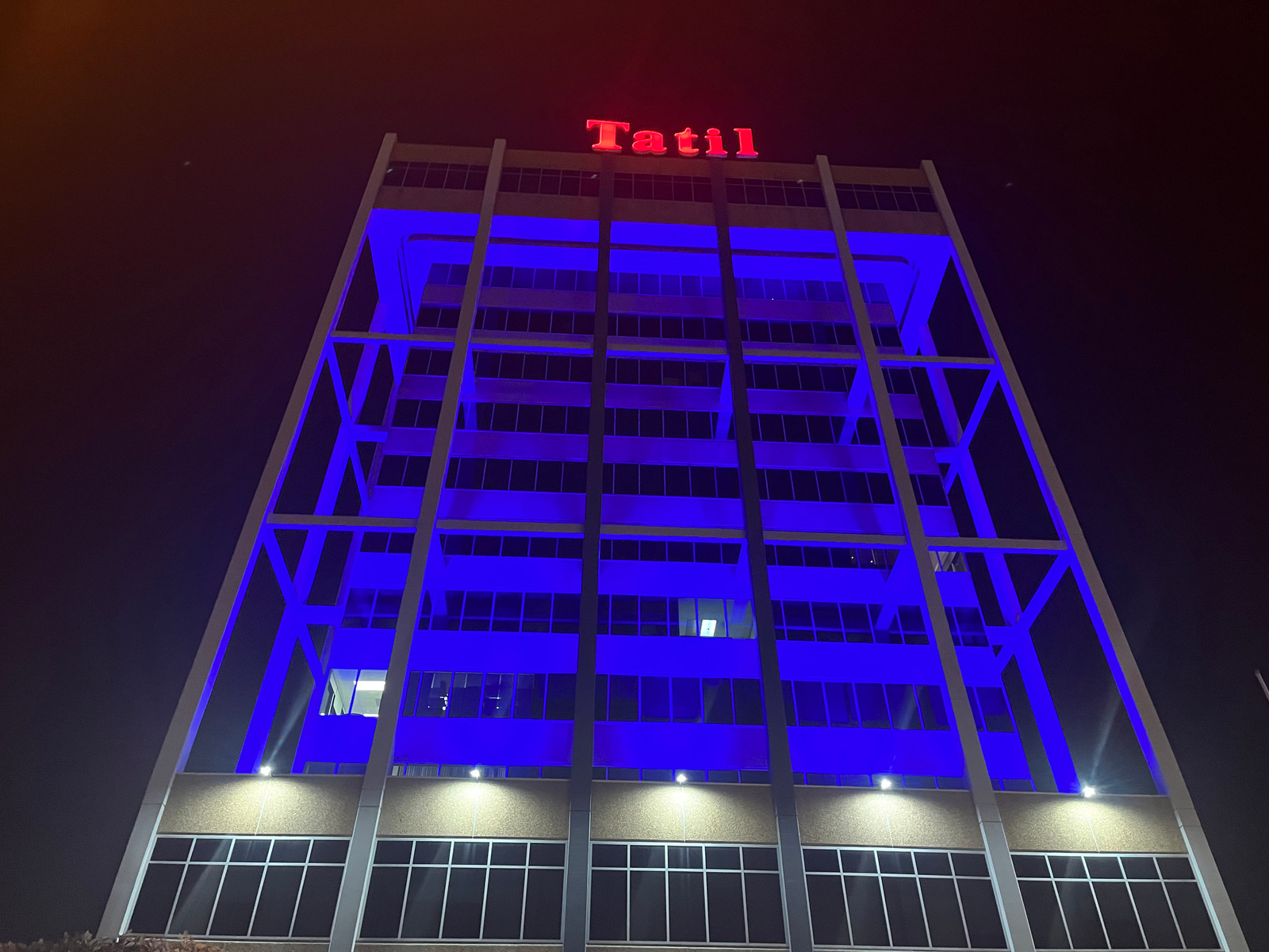 Edificio iluminado de azul que arriba dice "Tatil" en color rojo 