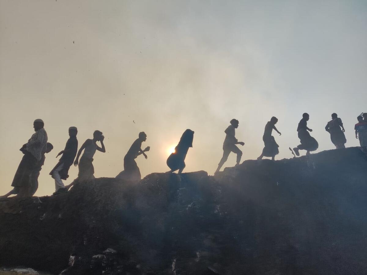 La silueta de personas que, en hilera, caminan en medio del humo provocado por un incendio.