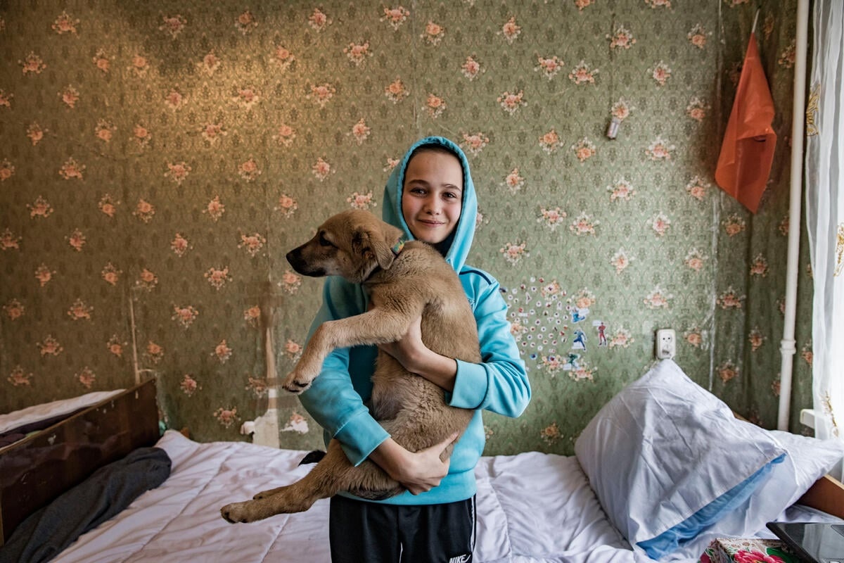 Un niño con capucha sostiene a su perro.