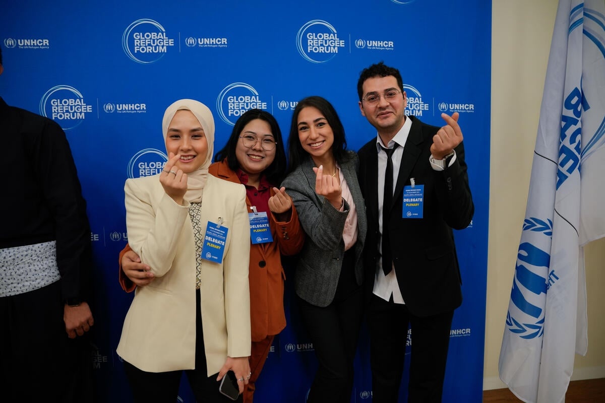 Tres mujeres y un hombre posan para una foto de grupo. Con sus manos hacen seña de corazón