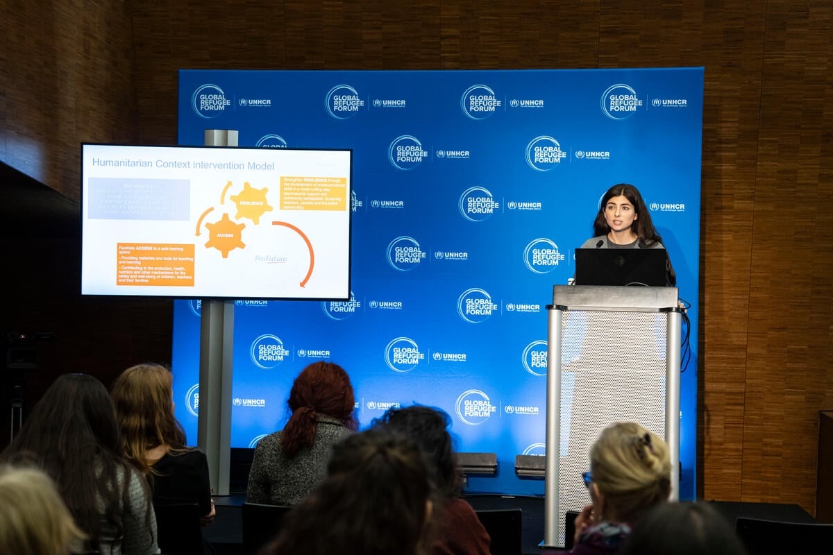 Una mujer toma la palabra en un podio, en el Foro Mundial sobre los Refugiados