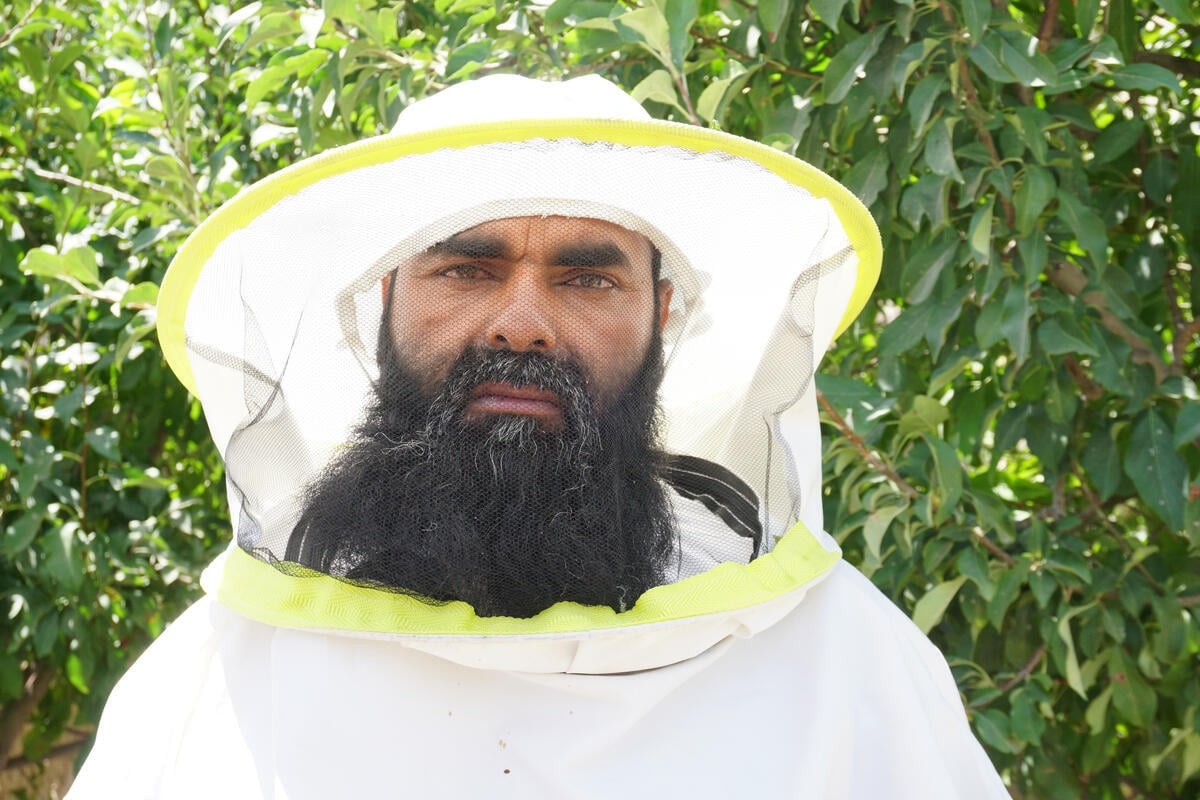 Un hombre con barba vestido con un traje blanco de apicultor