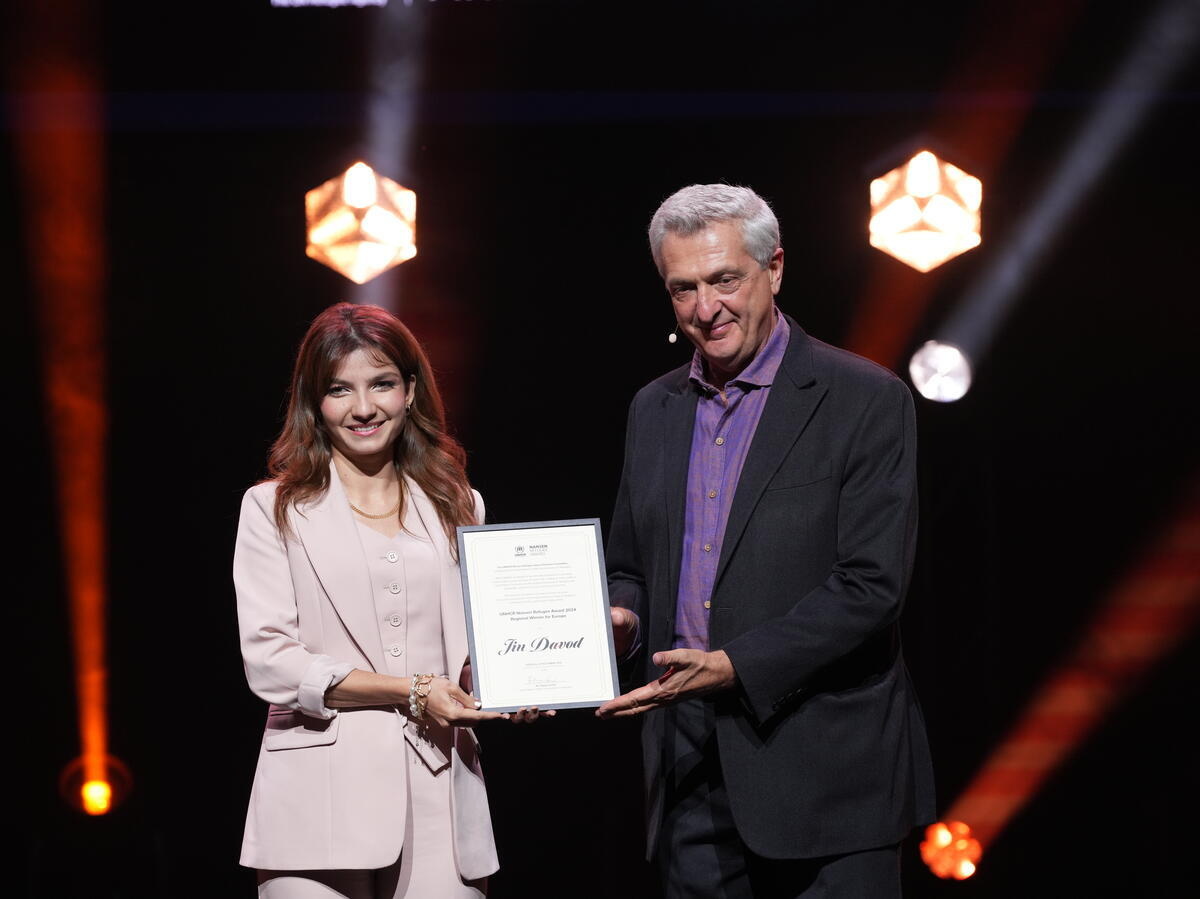 Un hombre entrega un certificado de premio a una mujer en el escenario