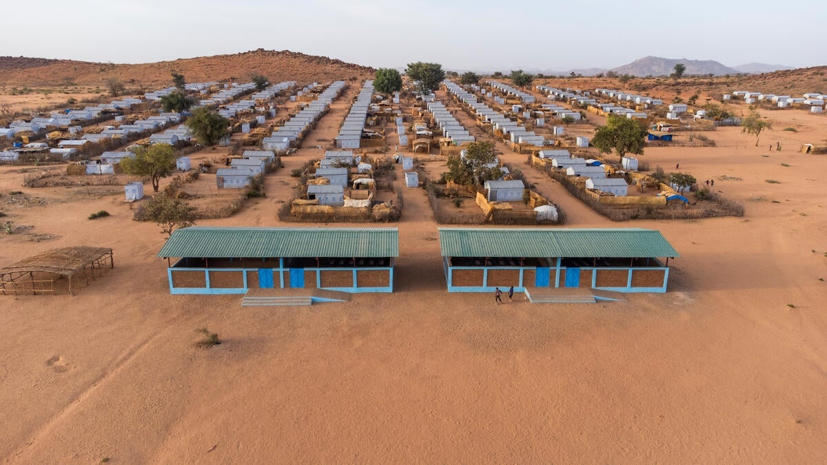 Vista aérea de hileras de alojamientos detrás de dos edificios más grandes rodeados de arena roja