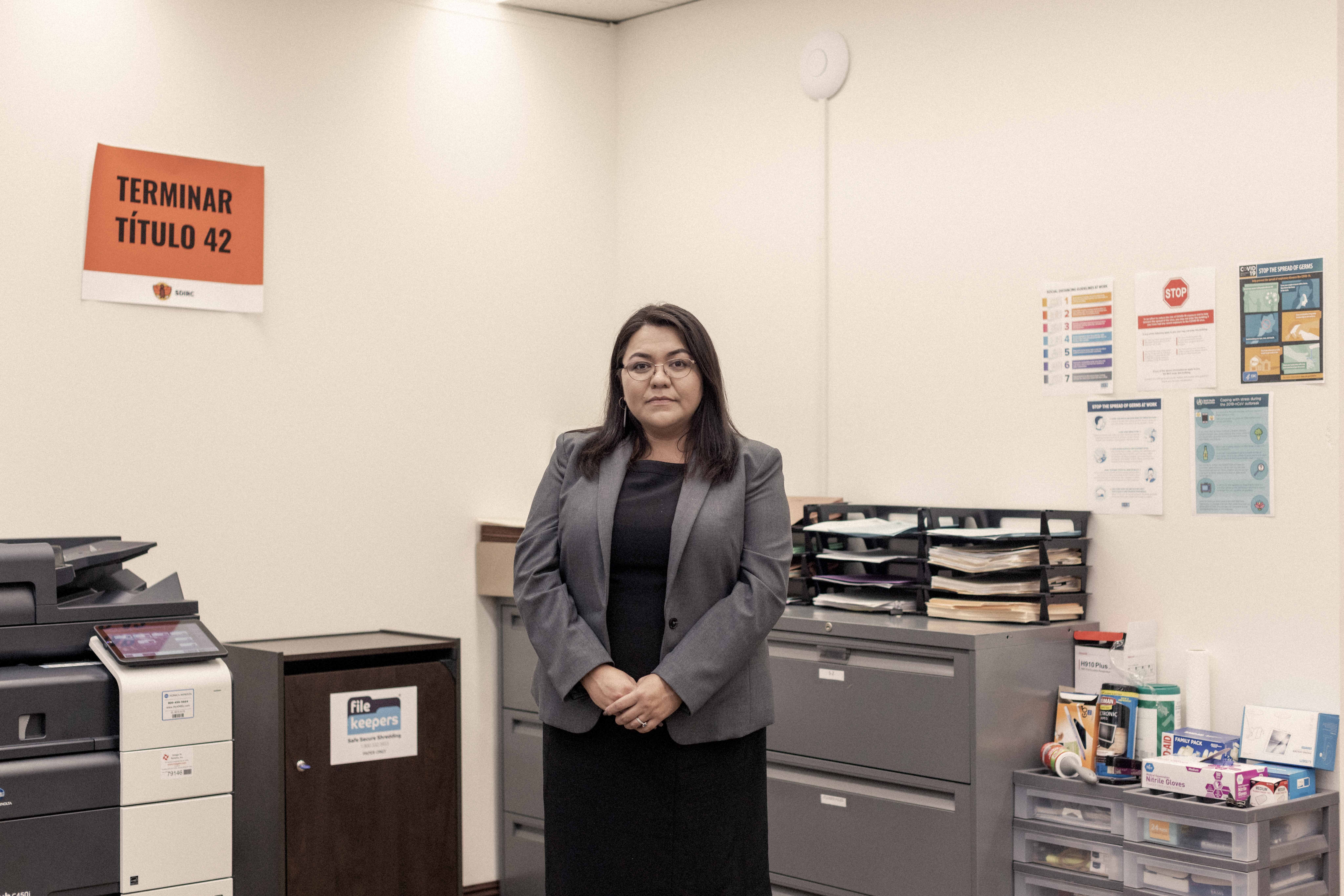 Una mujer en una oficina rodeada de gabinetes, un escritorio y una impresora