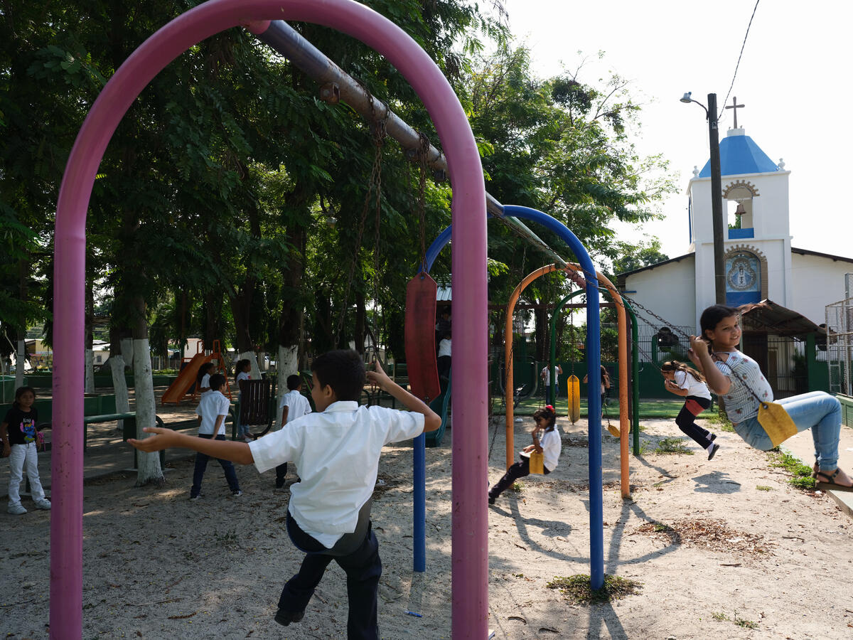 Niñas y niños se divierten en un parque comunitario con juegos