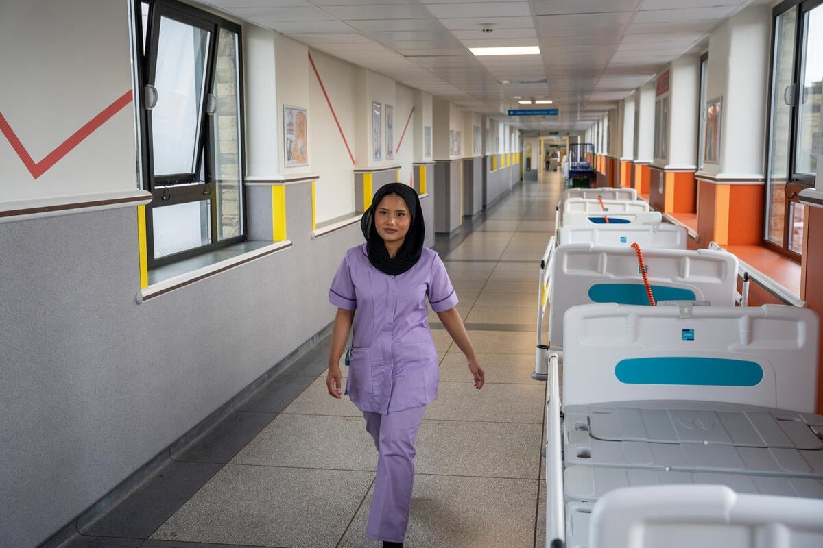 Una mujer en uniforme de enfermera camina en el pasillo de un hospital.