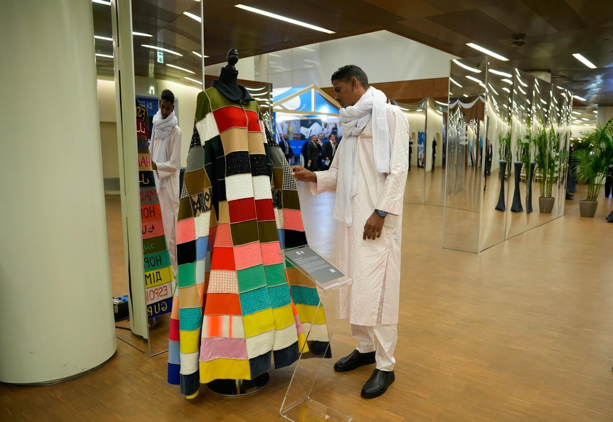 Un hombre vestido de blanco se detiene a ver una capa de colores
