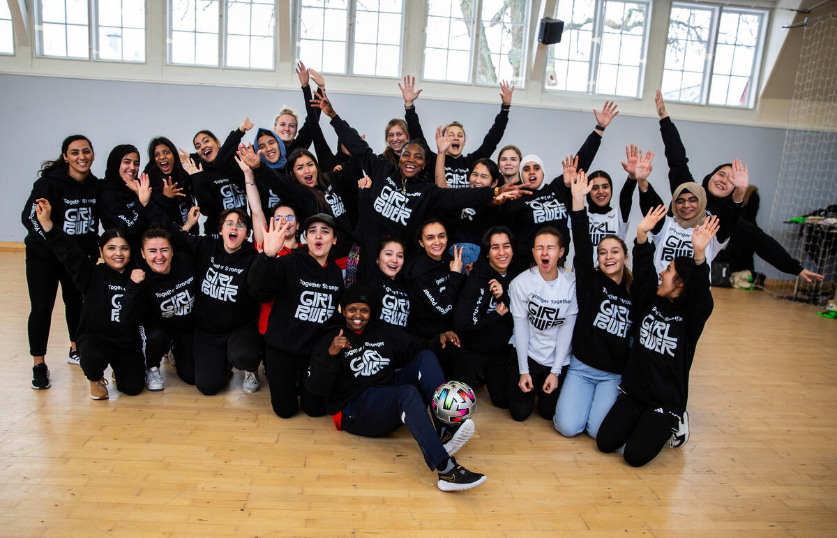 Un grupo de 30 mujeres con sudaderas negras posan para la foto en un salón de entrenamiento