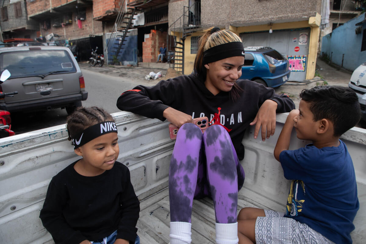 Andriuska y sus hihos conversan sonriendo en el cajón de un pick-up que usan como transporte.