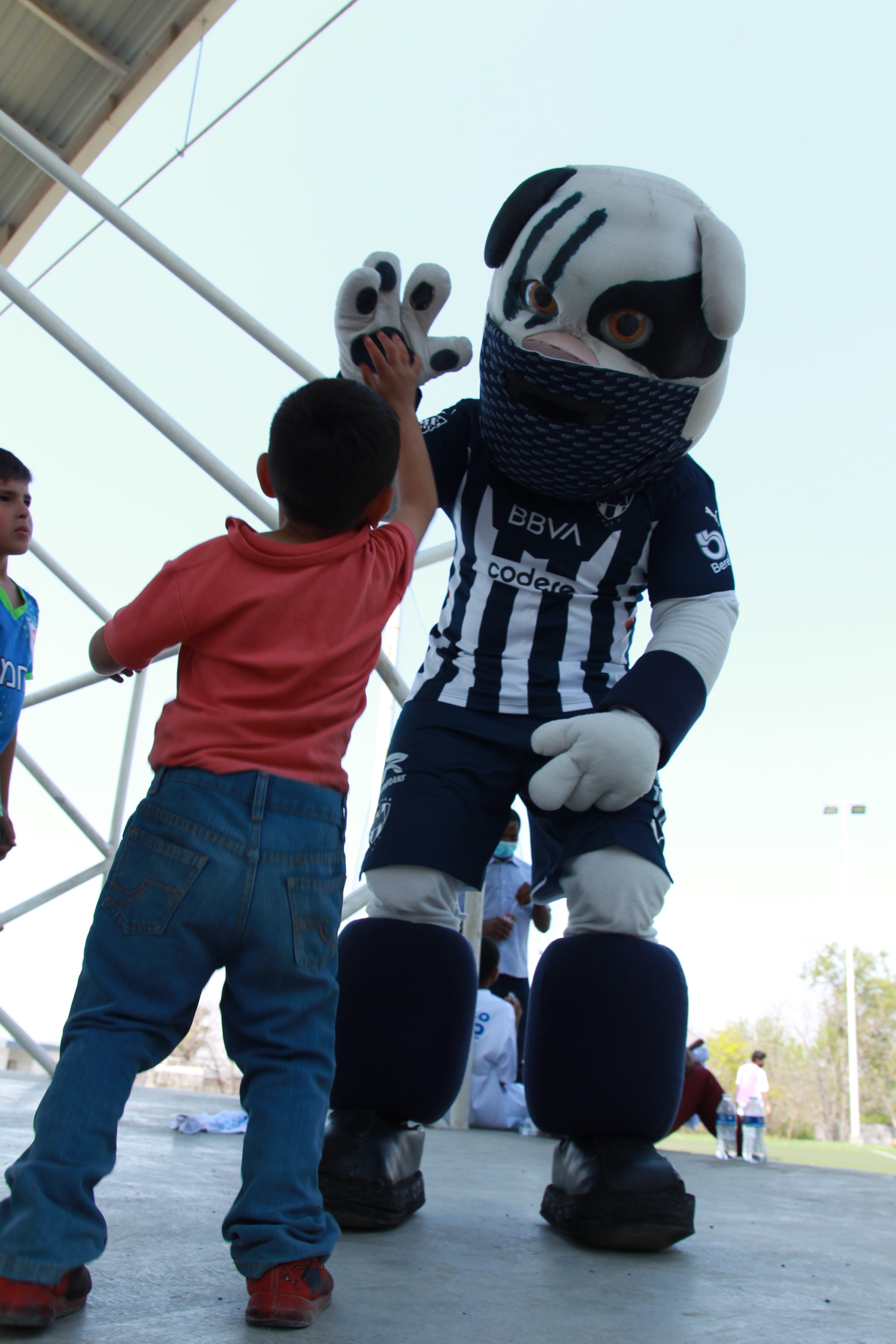 Monty, la mascota del club de fútbol Monterrey saluda a niño durante las ligas sociales.