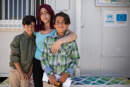 Una madre abraza a sus dos hijos; las tres personas miran fijamente a la cámara.