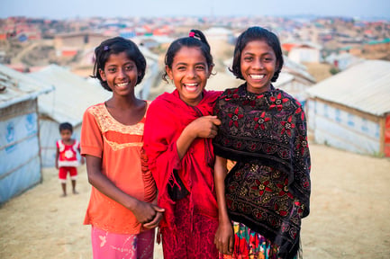 Tres niñas refugiadas sonríen a la cámara en el campamento de Kutupalong, Bangladesh.