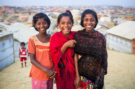 Tres niñas refugiadas sonríen a la cámara en el campamento de Kutupalong, Bangladesh.